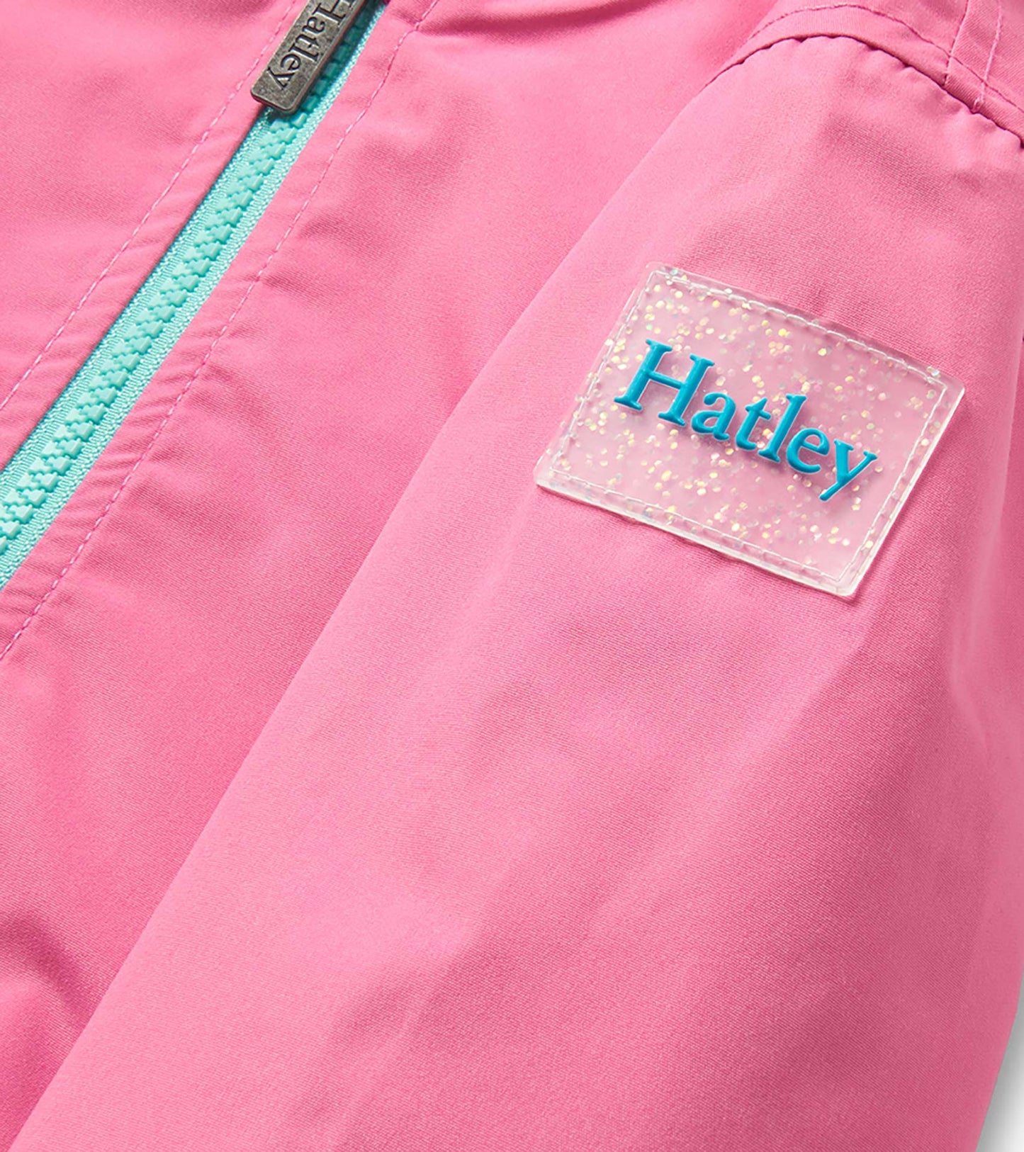 Pink girls rain jacket with turquoise zipper and clear glittery chest patch
