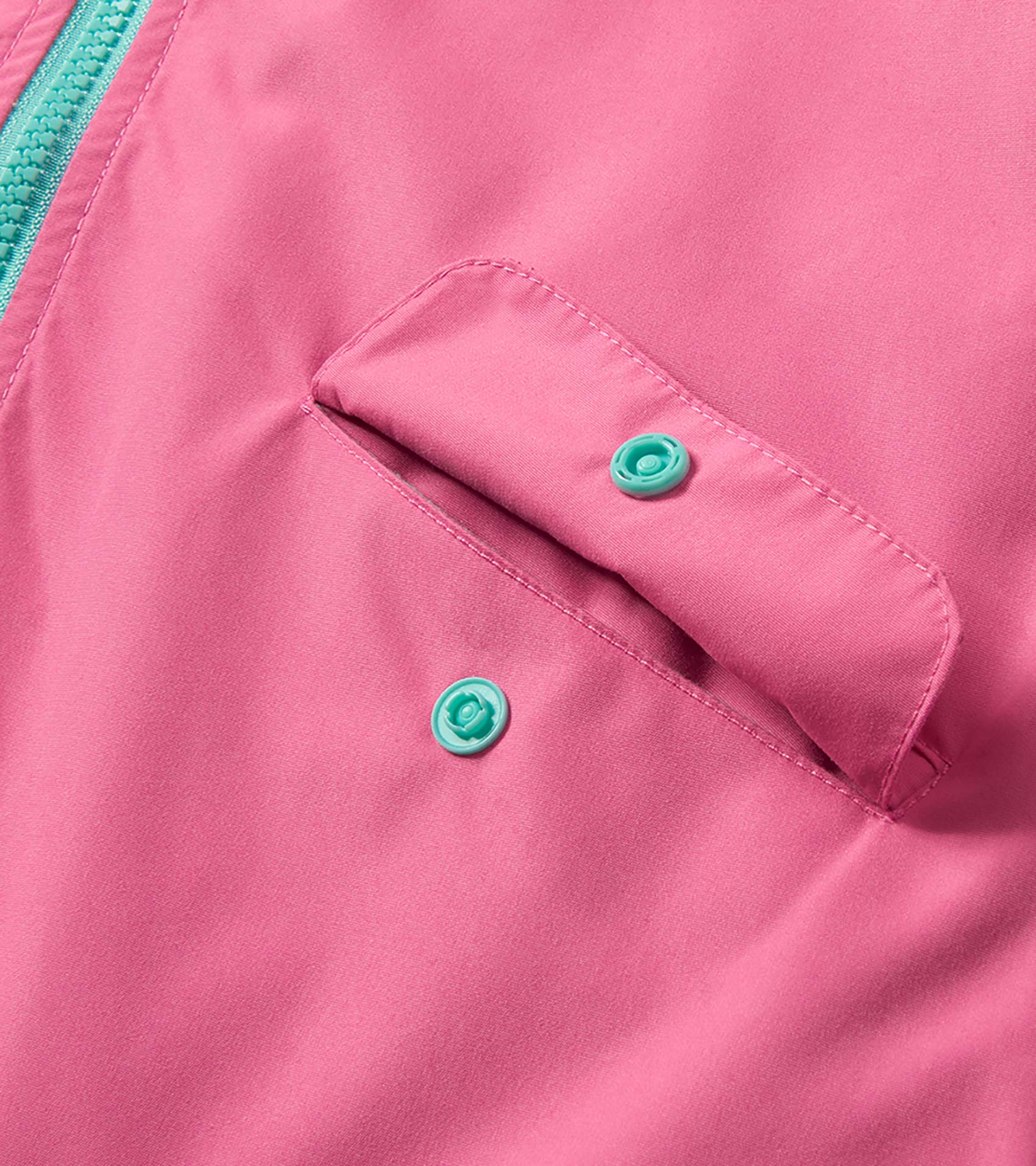 Close-up of a pink rain jacket with teal zipper and snap buttons, showing a flap pocket detail.