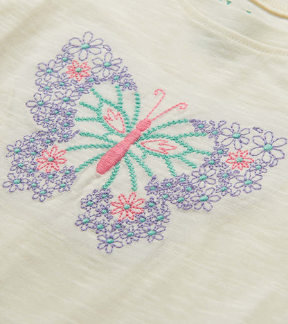 Cream T-shirt with embroidered pink and purple butterfly surrounded by flowers, close-up view