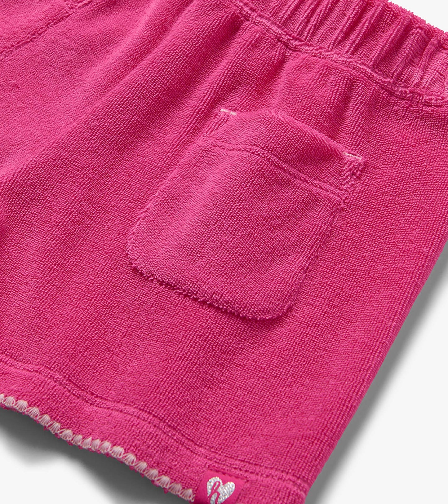 Pink terry cloth shorts with elastic waistband and back pocket, close-up view