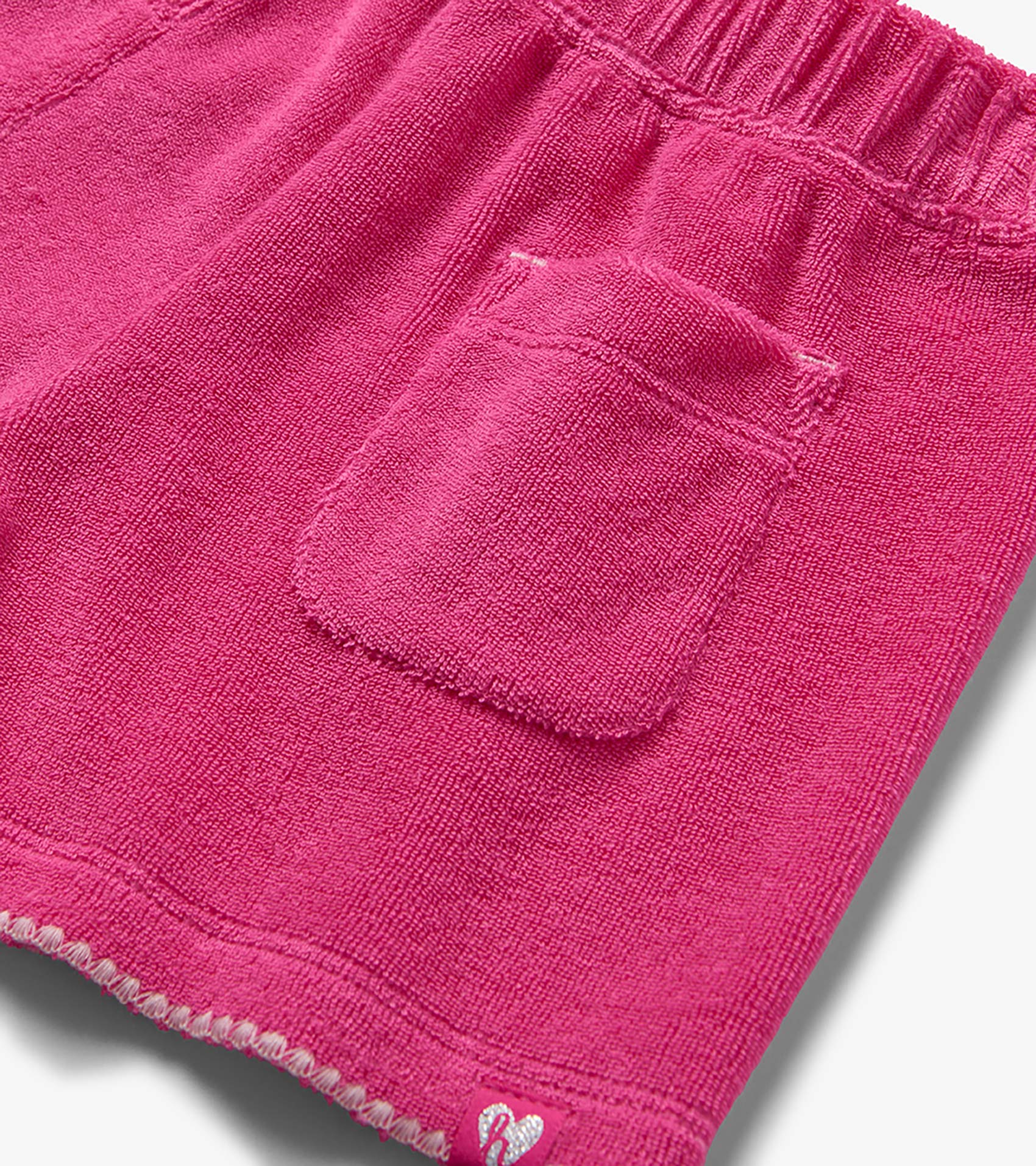 Pink terry cloth shorts with elastic waistband and back pocket, close-up view