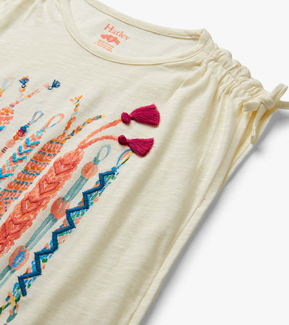 Cream girls top with colorful friendship bracelet print, ruched shoulder ties, and magenta tassels