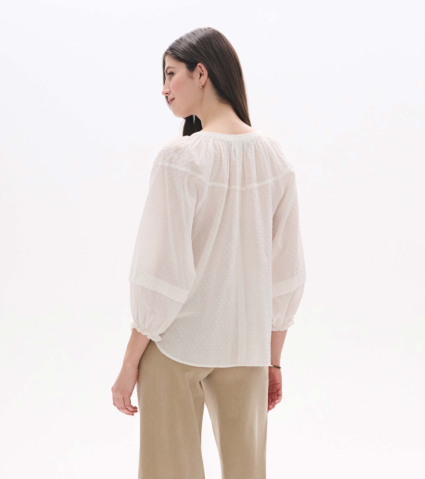 Back view of a blush Swiss dot sheer blouse with long puff sleeves and gathered yoke