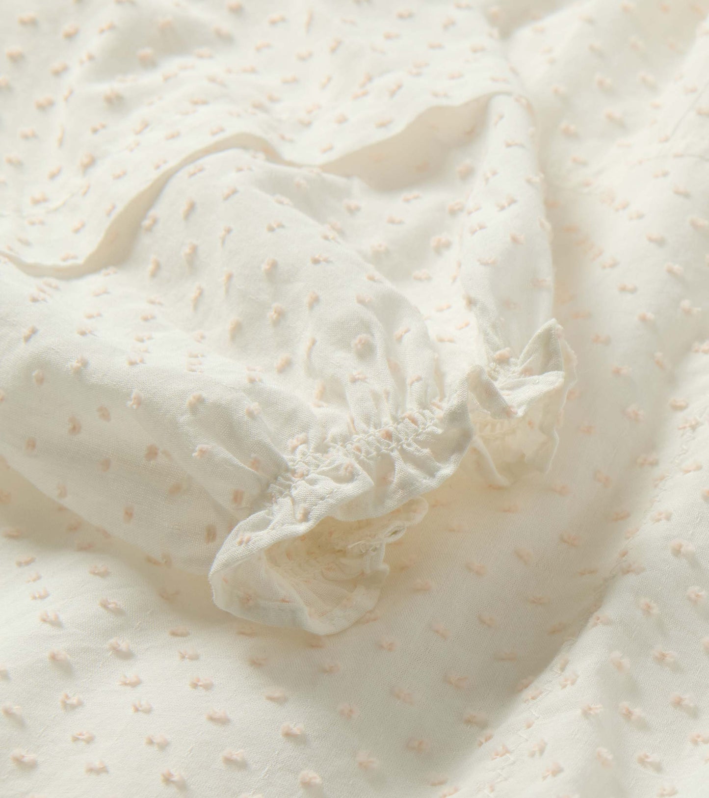 Blush Swiss dot fabric with tiny raised polka dots and gathered elastic cuff detail