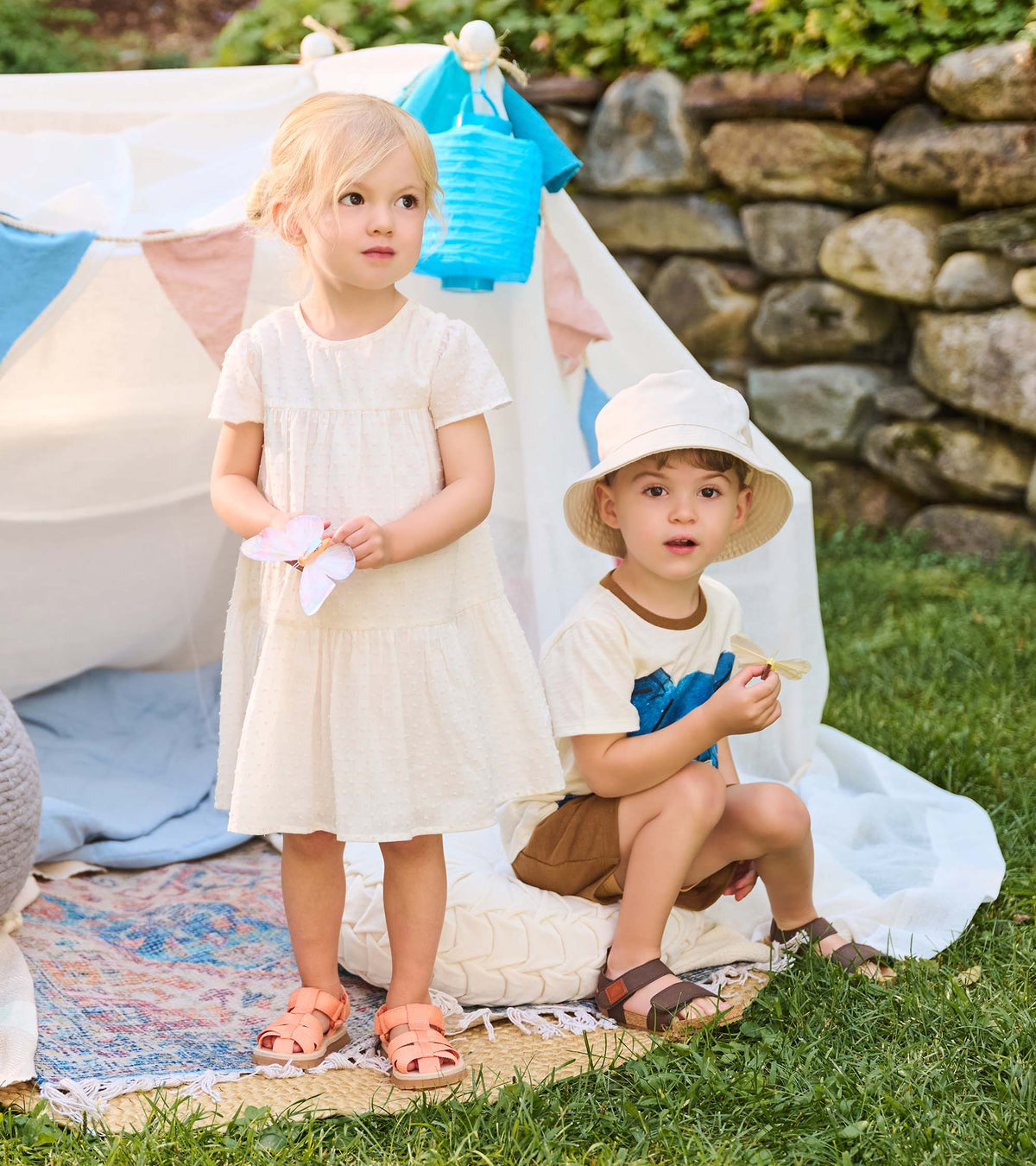 Toddler wearing an ivory Swiss dot puff sleeve dress standing beside another child outdoors