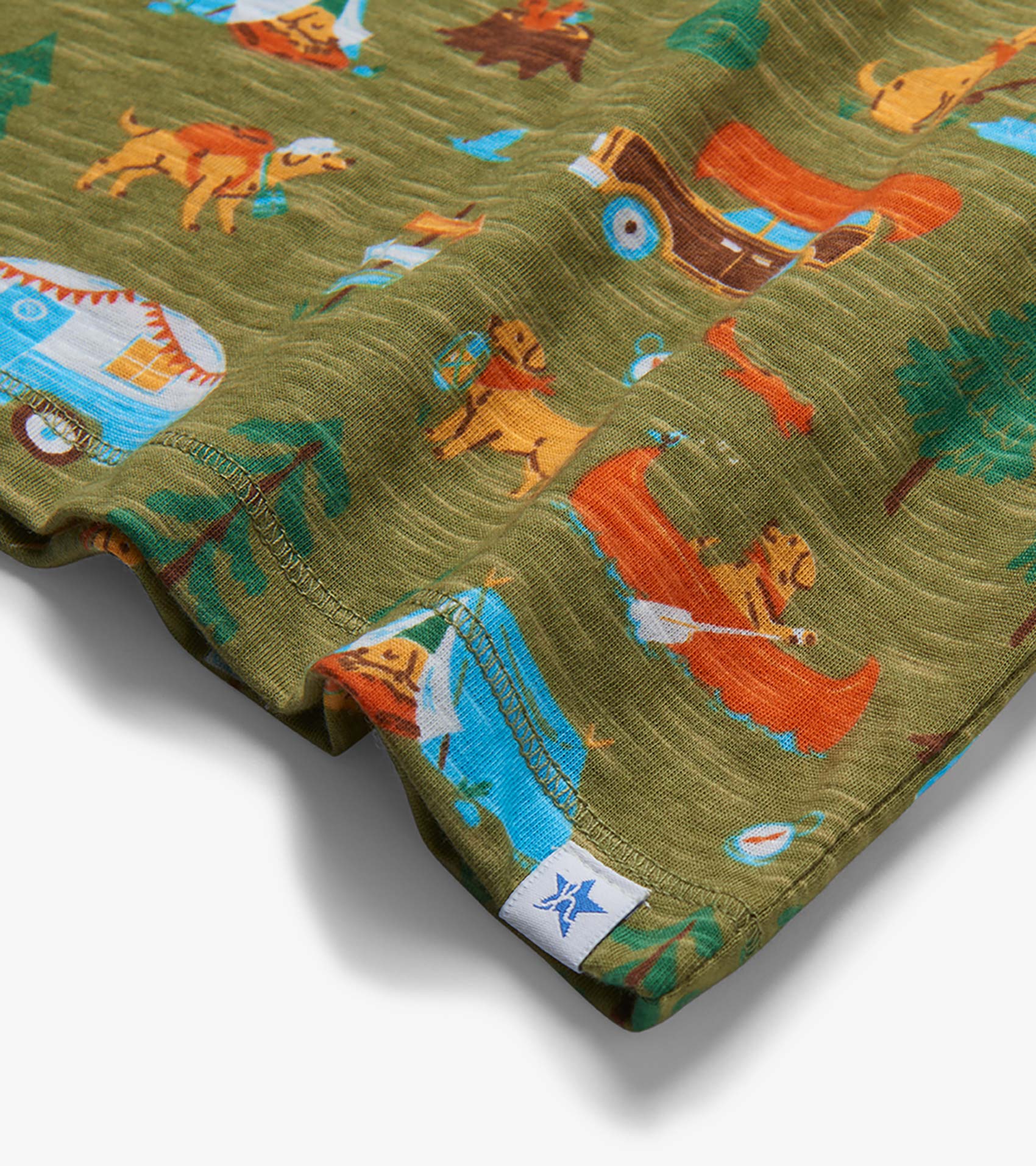 Olive green knit shorts with colorful camping dog and tent print, close-up of hem and stitching