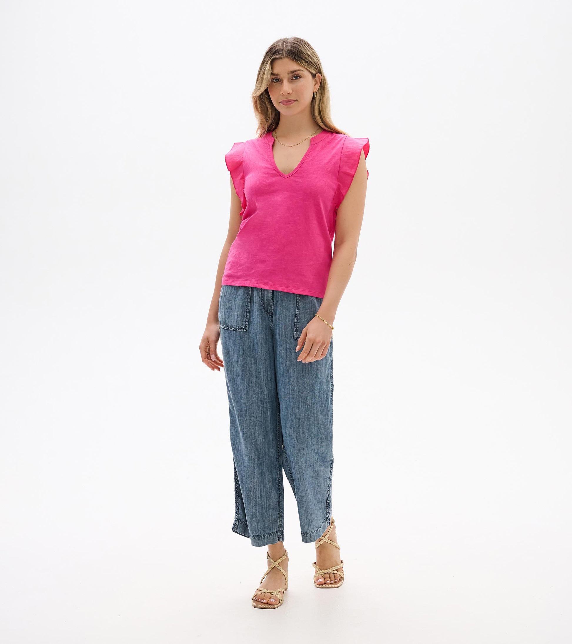 Bright pink sleeveless V-neck top with ruffled shoulders, shown on a model front view