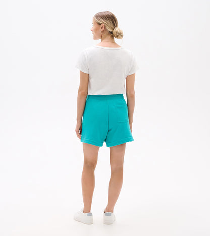 Back view of turquoise shorts with elastic waistband, rolled hems, and back pocket, worn with a white T-shirt and sneakers