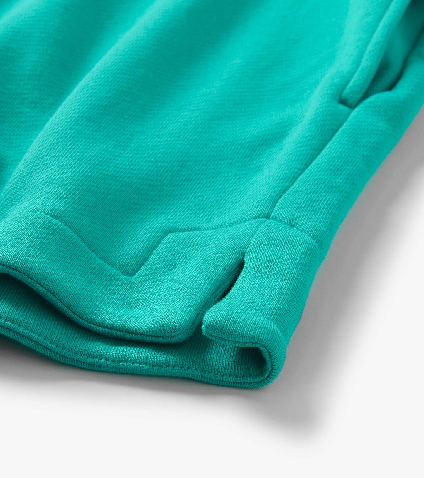 Close-up of teal knit shorts hem with folded cuff and visible stitching