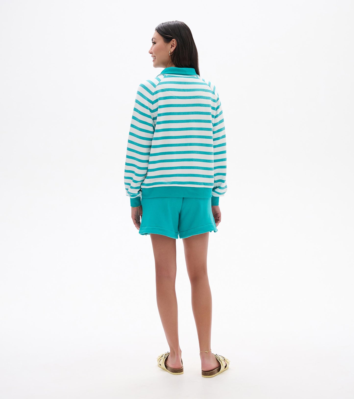 Back view of a green and white striped mock neck pullover with teal collar, cuffs, and hem