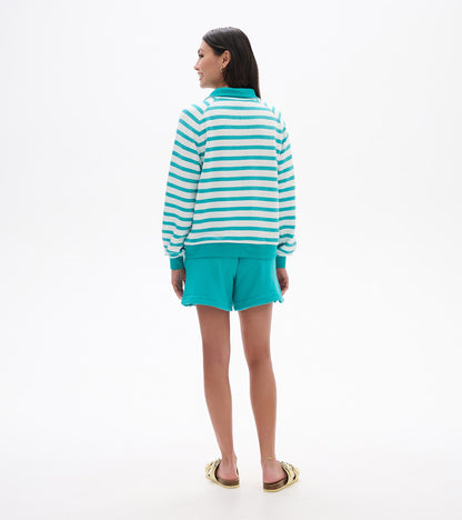 Back view of a green and white striped mock neck pullover with teal collar, cuffs, and hem