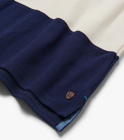 Folded navy and cream color block polo shirt with textured knit fabric and small chest logo patch