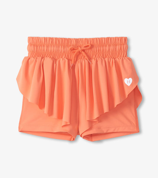 Coral girls running shorts with elastic waistband, drawstring, and layered ruffle overlay, front view