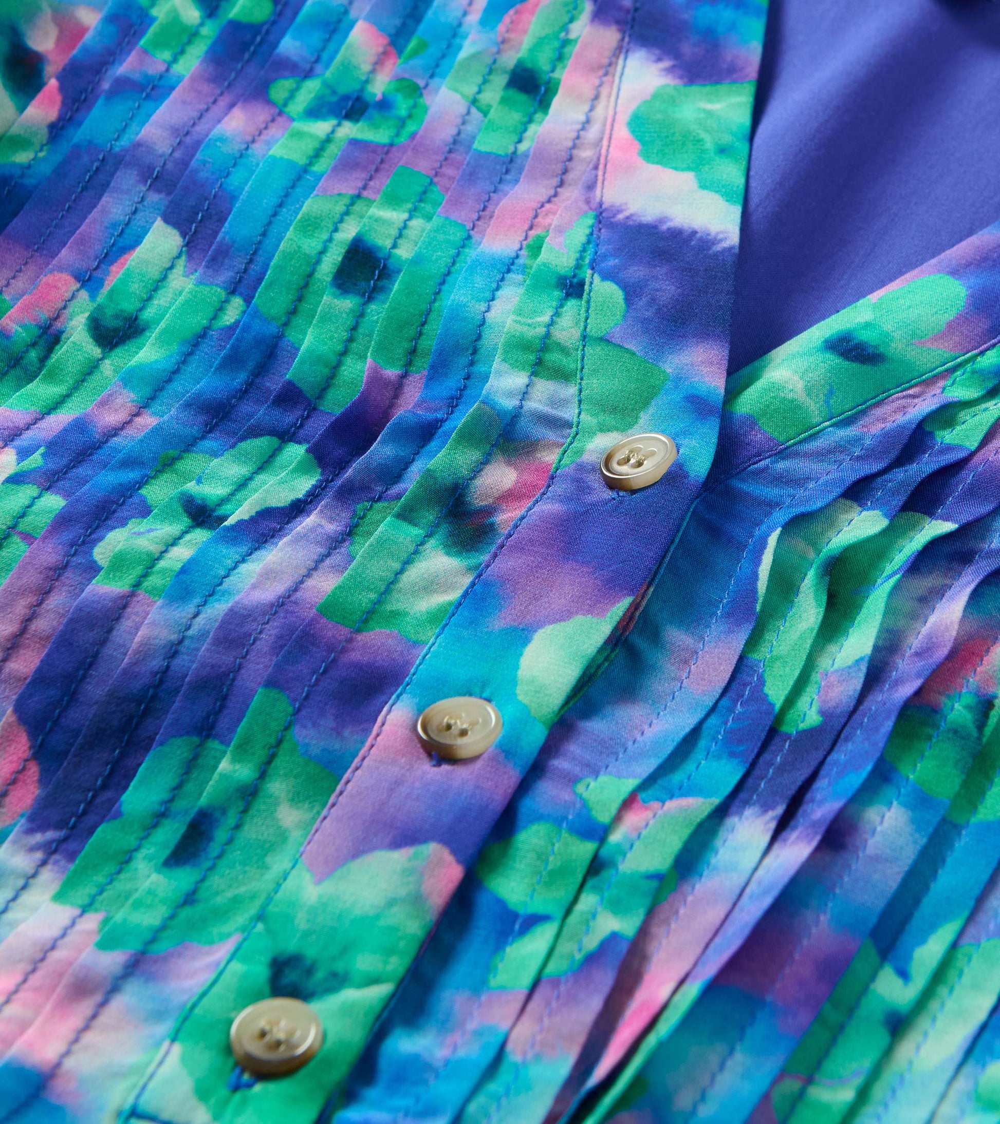 Close-up of blue, teal and purple floral print with pintuck pleats and front buttons