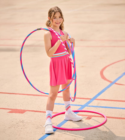 Girl in bright pink pleated active dress with striped waistband, standing with colorful hula hoops