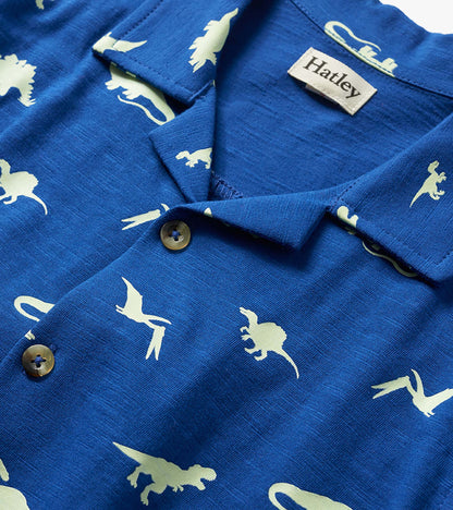 Blue boys button-down shirt with white dinosaur print and visible buttons, close-up view