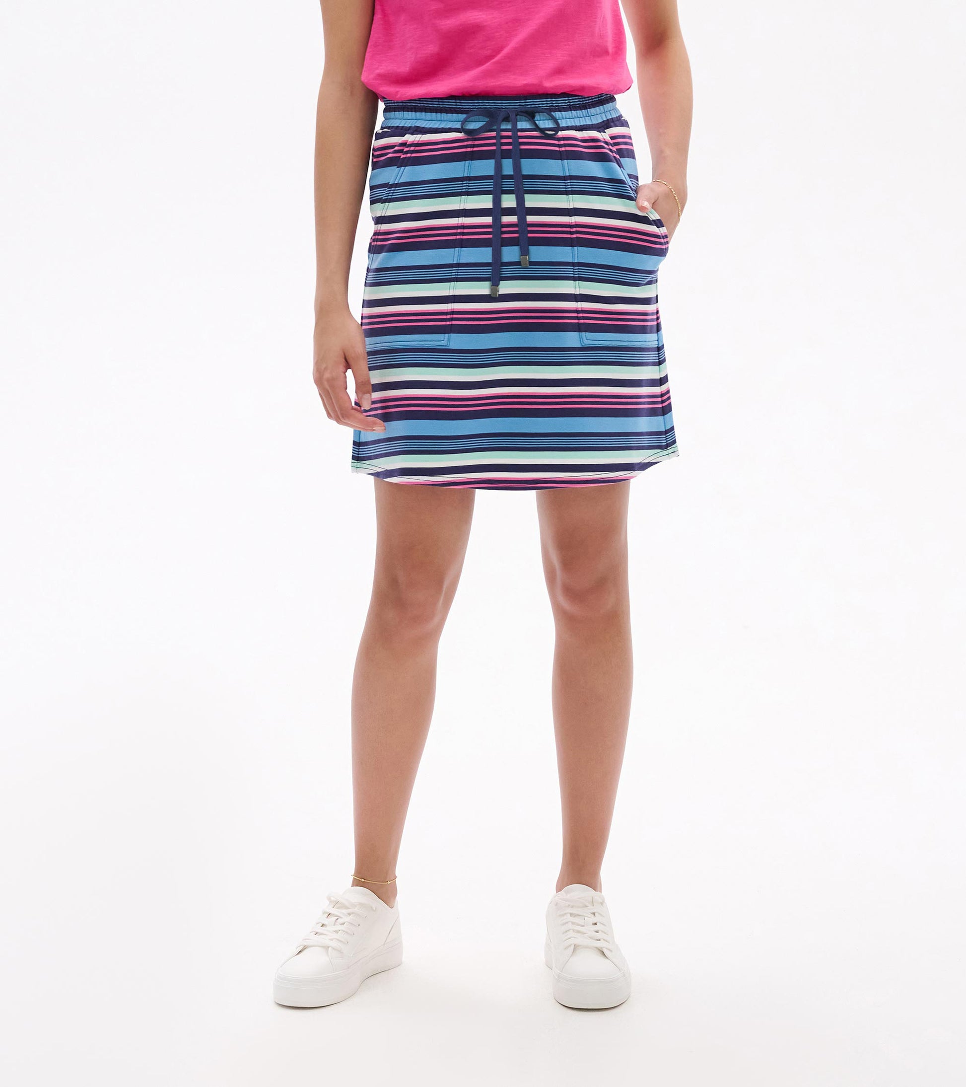 Woman wearing a striped blue, pink, and white drawstring skirt with side pockets, front view