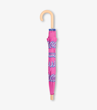 Folded pink kids umbrella with blue heart burst pattern and tan curved handle