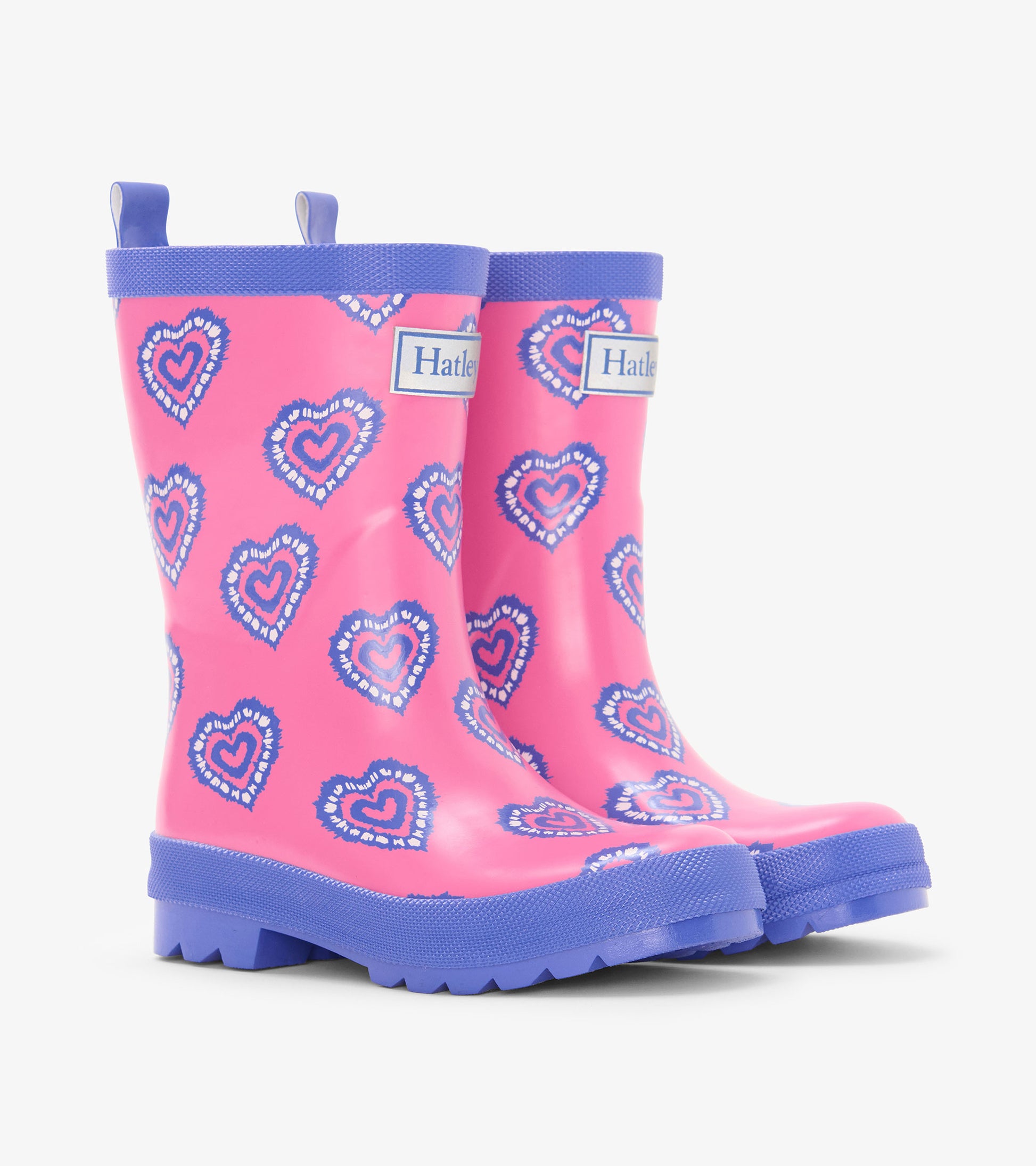 Pink kids rain boots with blue heart print, blue trim, and pull tabs, shown in side view