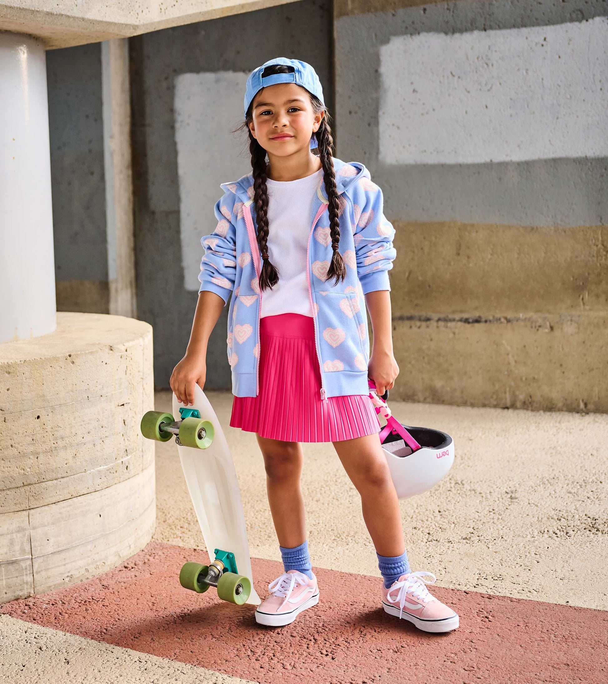 Girl wearing a light blue heart print zip hoodie with a pink zipper, shown open with a white top and pink skirt