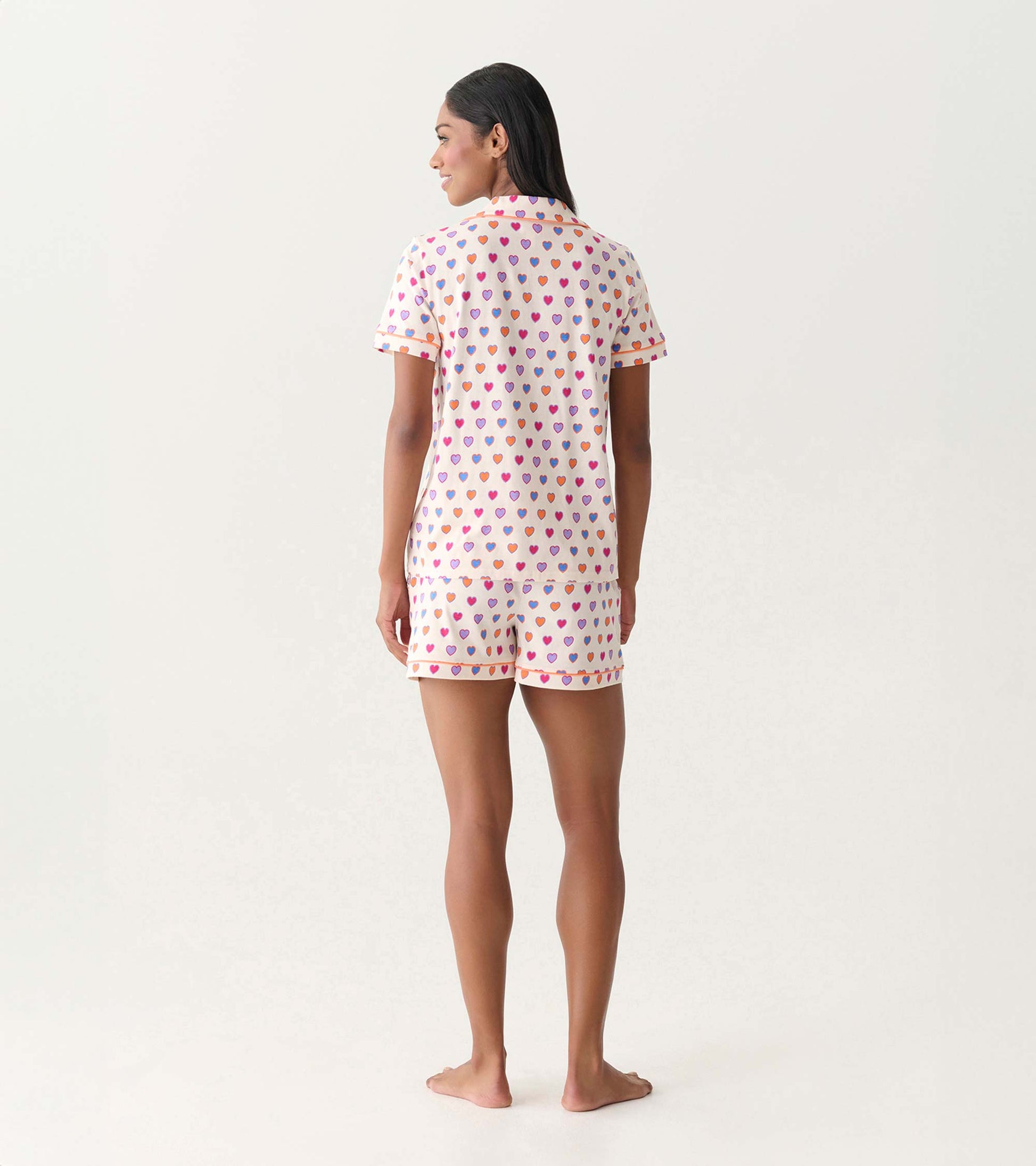Back view of a short-sleeve pajama set with white fabric and multicolored heart print, matching shorts.