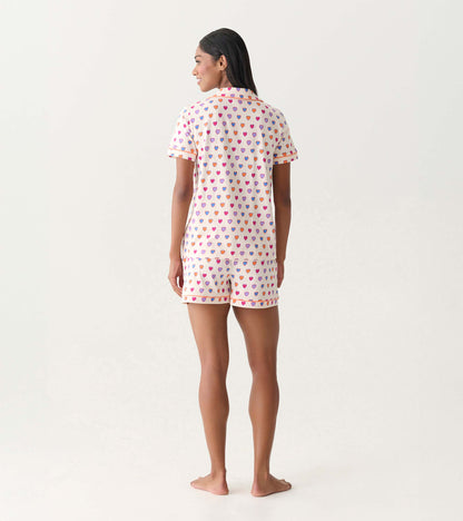 Back view of a short-sleeve pajama set with white fabric and multicolored heart print, matching shorts.