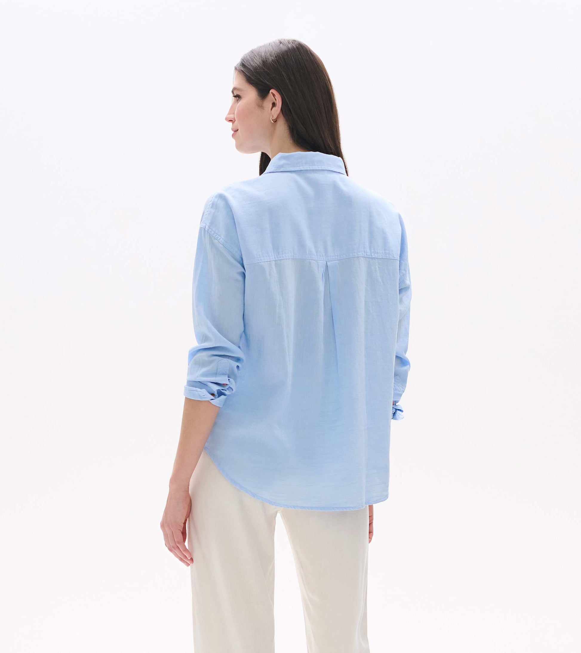 Light blue chambray button-down shirt shown from the back, with rolled sleeves and a relaxed fit.