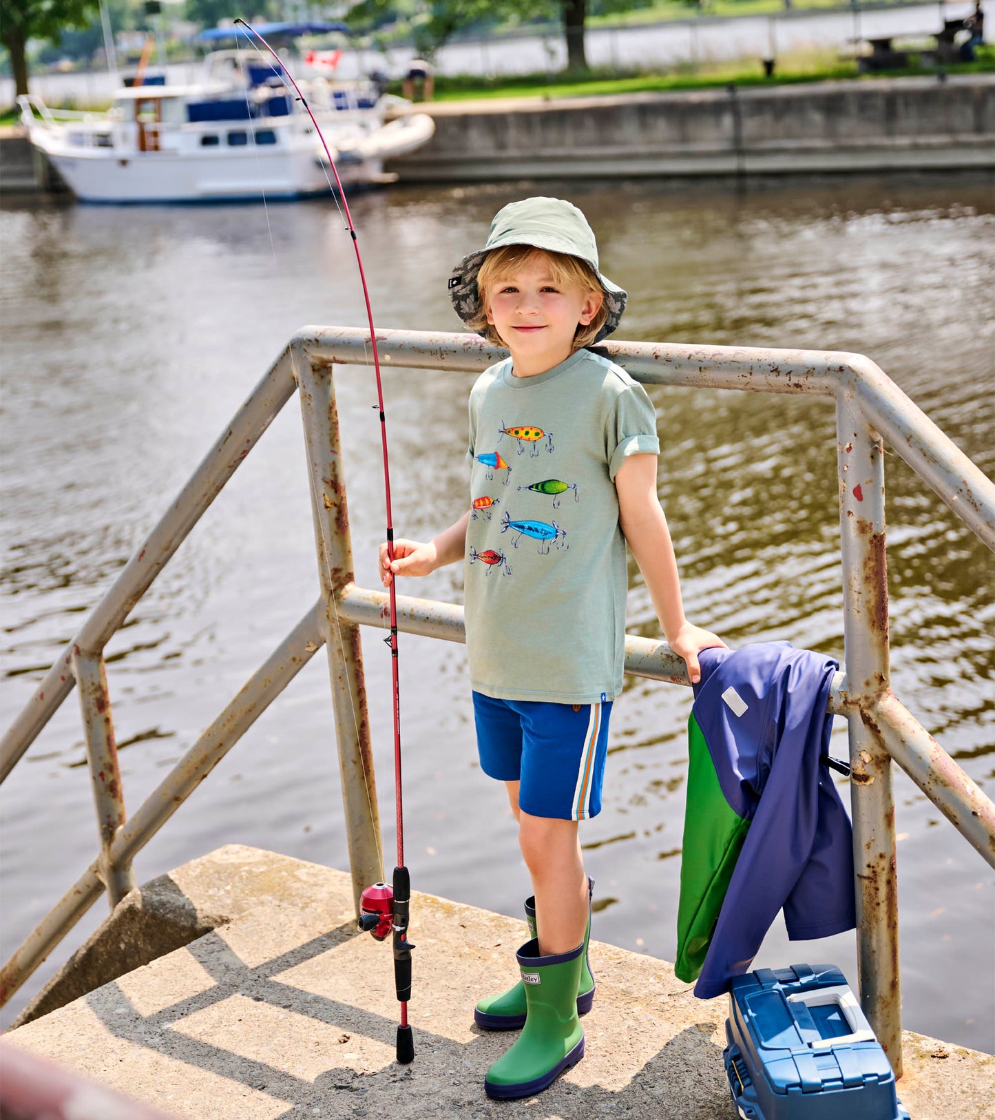 Blue pull-on shorts with side stripes worn by a child standing by the water, front view