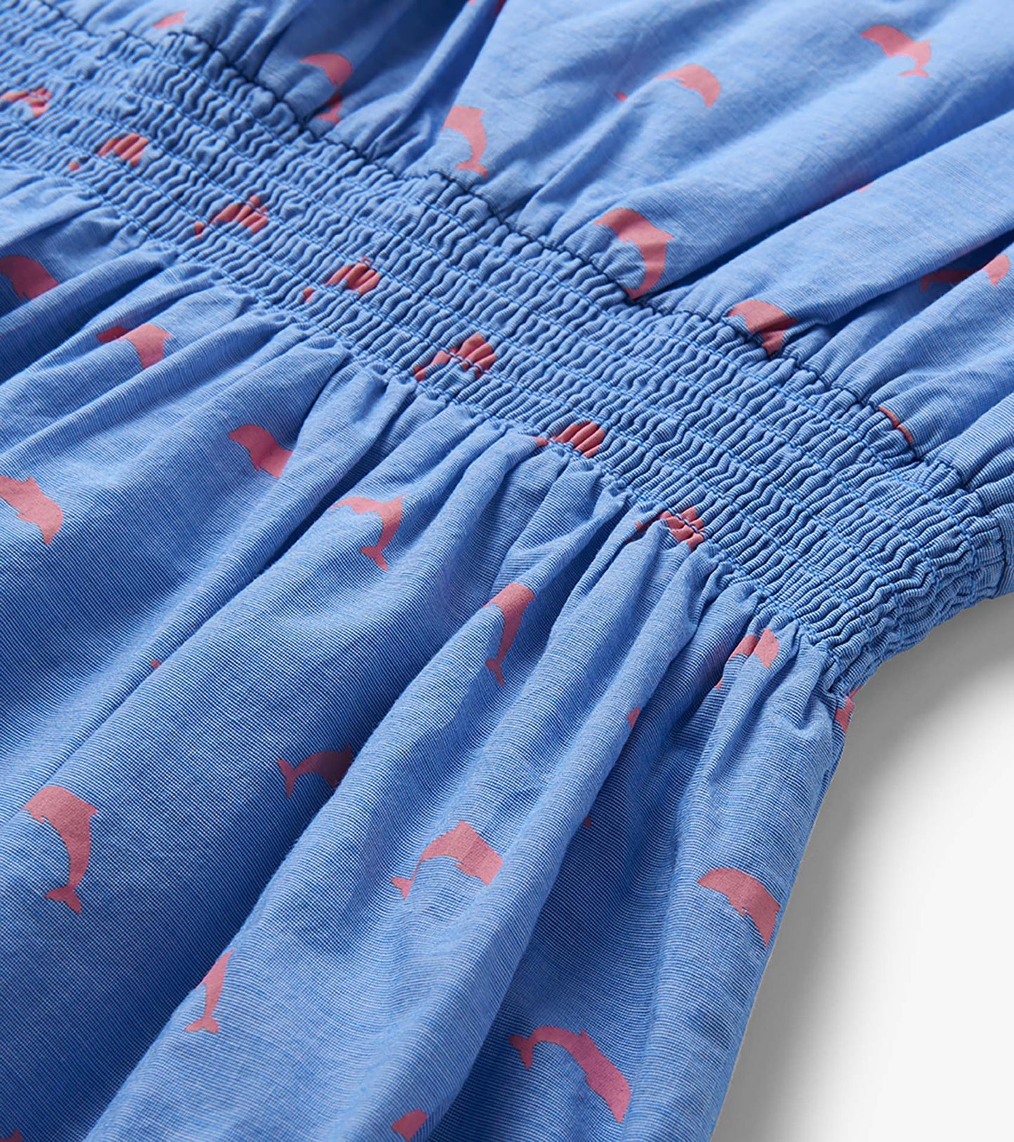 Blue woven girls dress with pink dolphin print and smocked waist detail