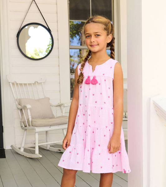 Girl wearing a pink gingham tiered dress with small berry print and tassel ties, shown from the front