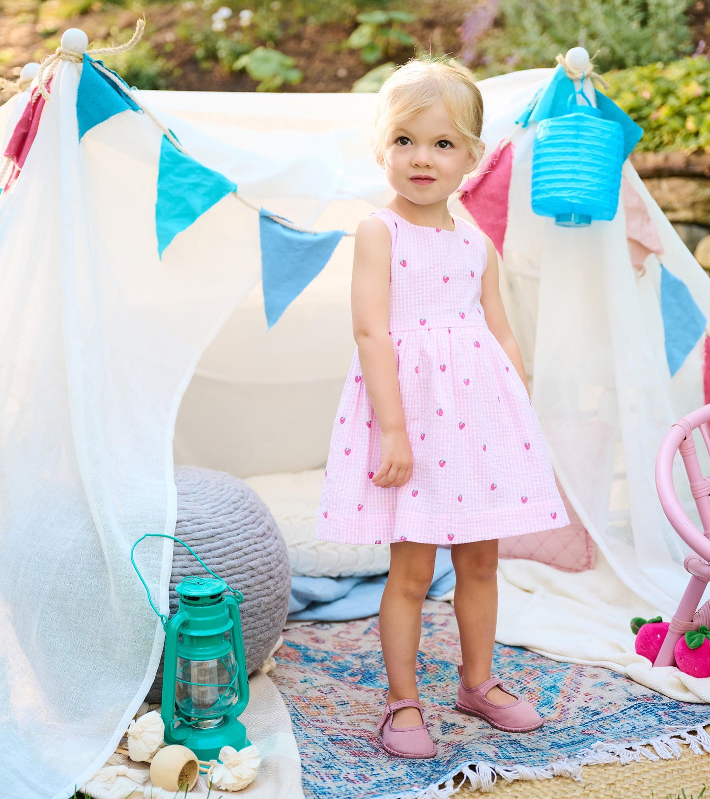Toddler girl wearing a sleeveless pink gingham dress with tiny berry motifs and a gathered skirt