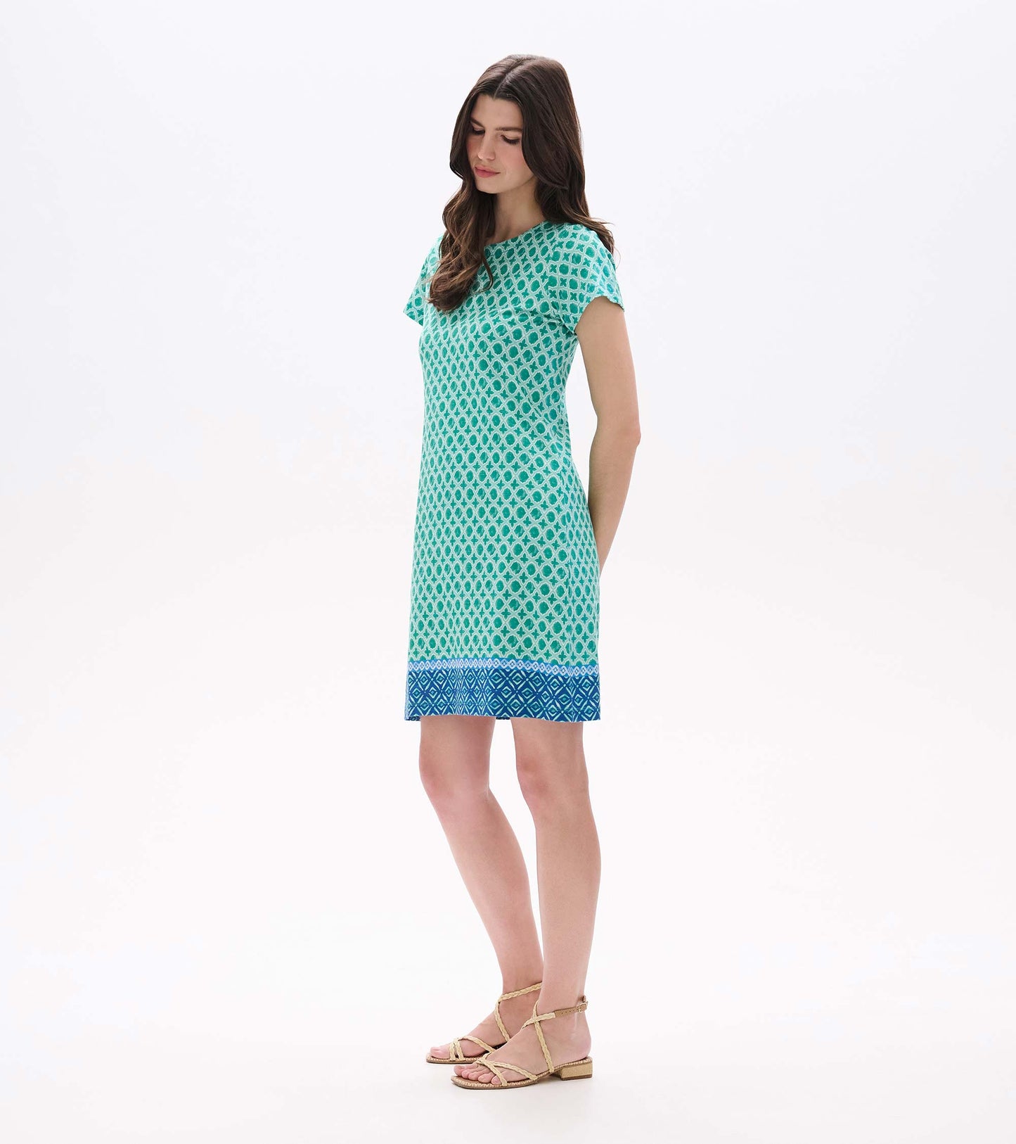 Side front view of green printed tee dress with short sleeves and blue patterned hem