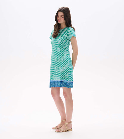 Side front view of green printed tee dress with short sleeves and blue patterned hem