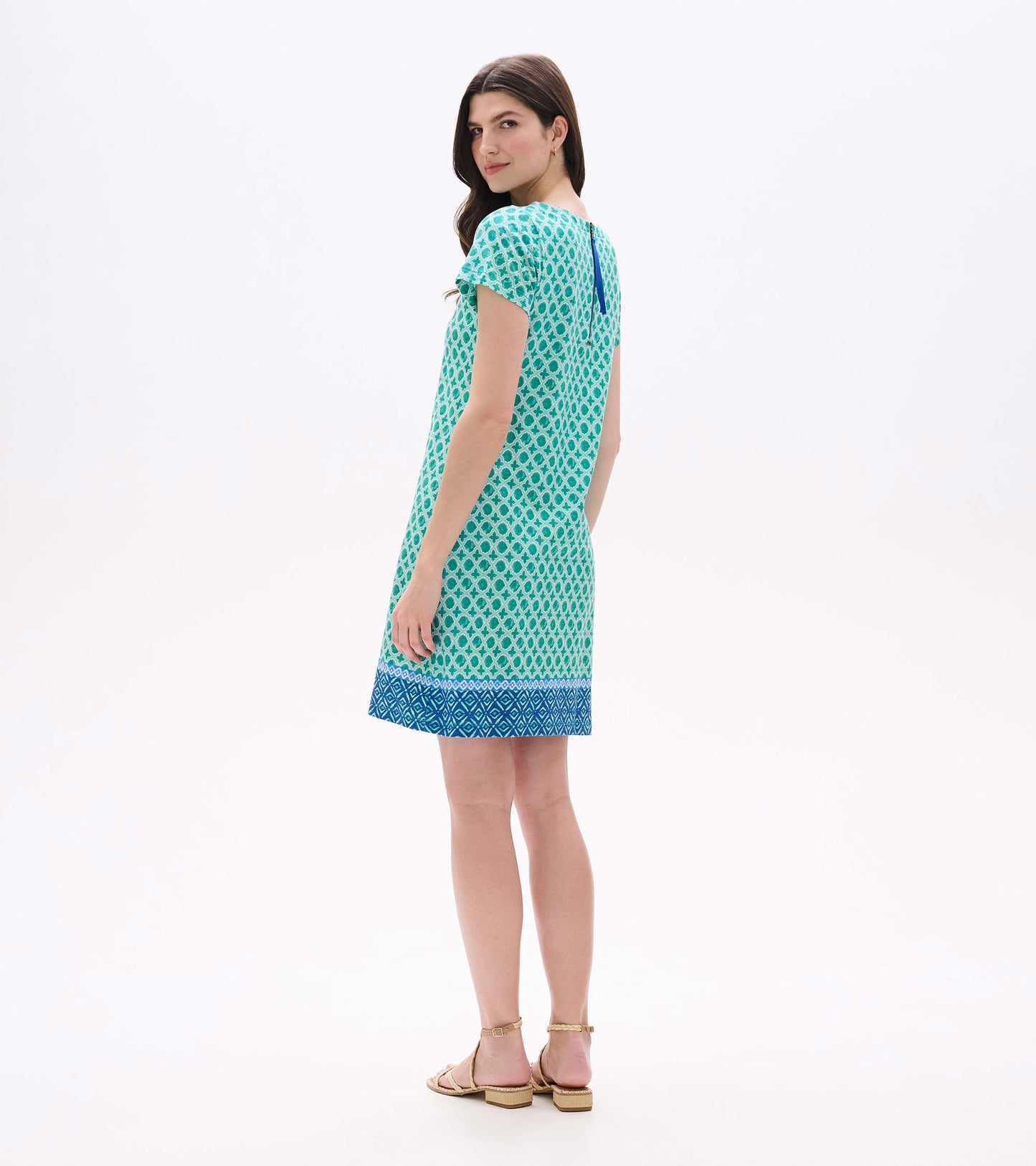 Back angled view of green medallion print tee dress with blue border hem and exposed back zipper