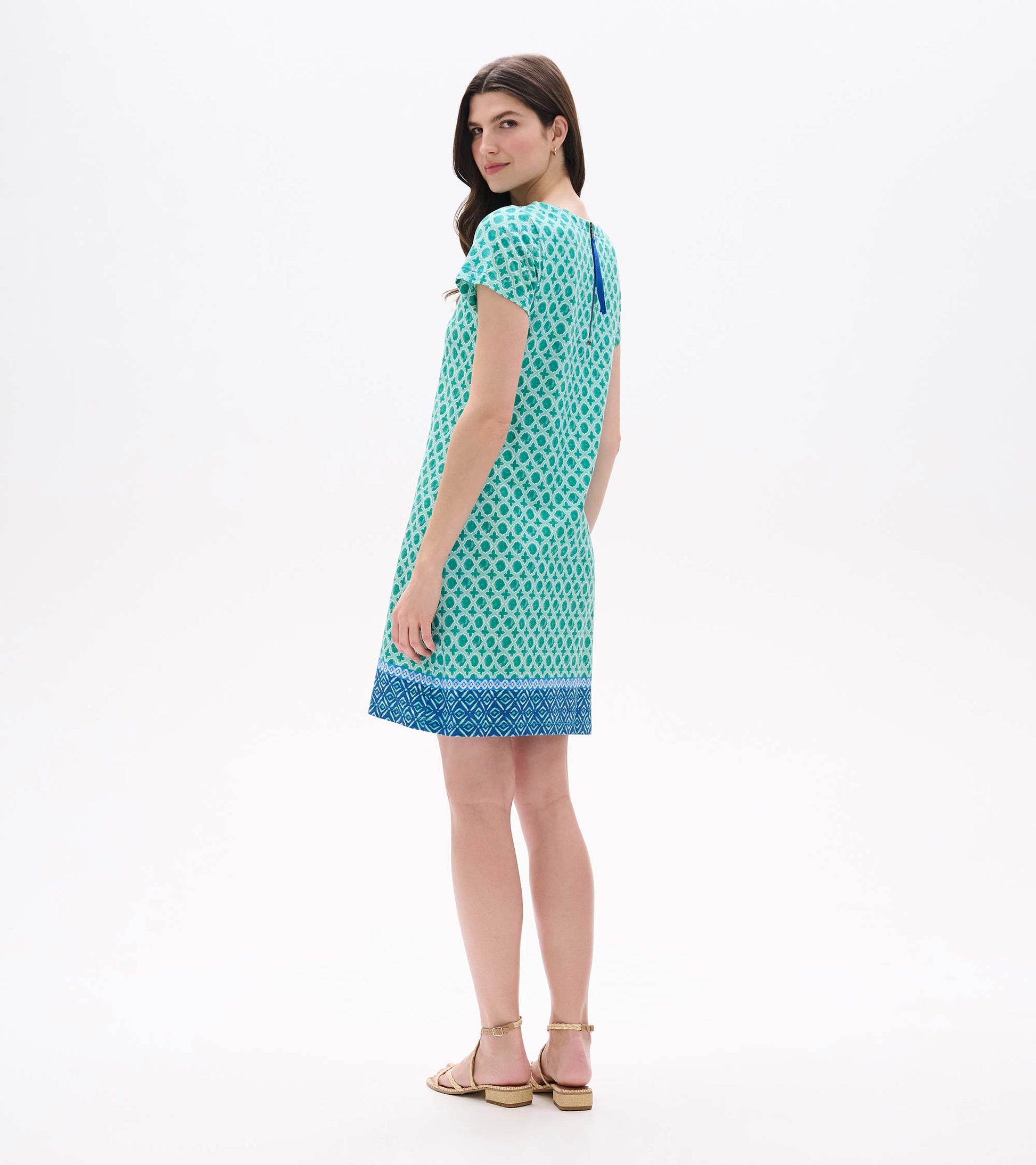 Back angled view of green medallion print tee dress with blue border hem and exposed back zipper