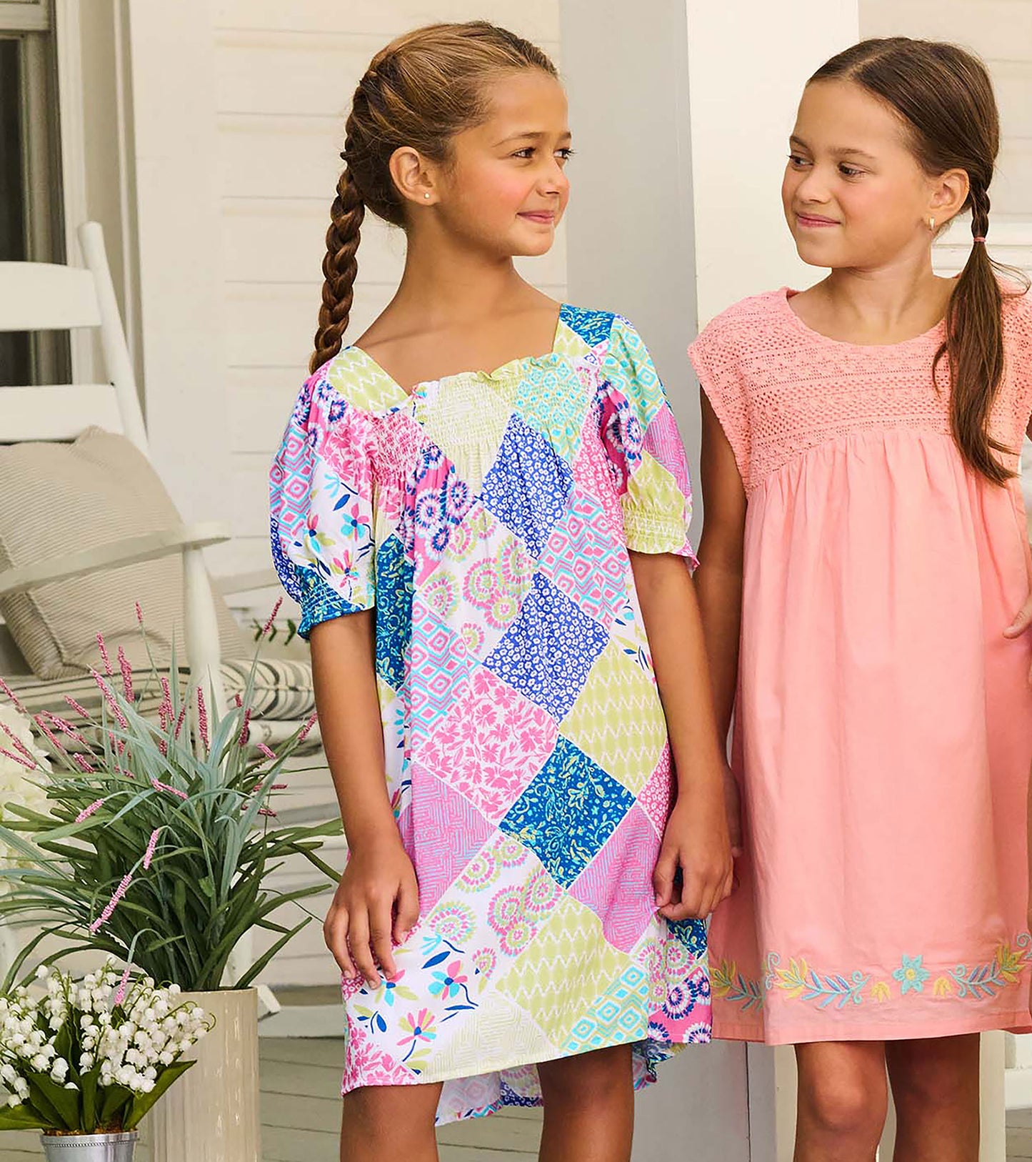 Girl wearing patchwork smocked dress with puff sleeves and square neckline, shown from the front