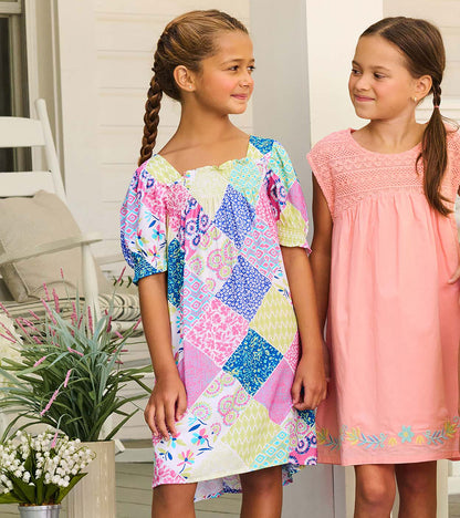 Girl wearing patchwork smocked dress with puff sleeves and square neckline, shown from the front