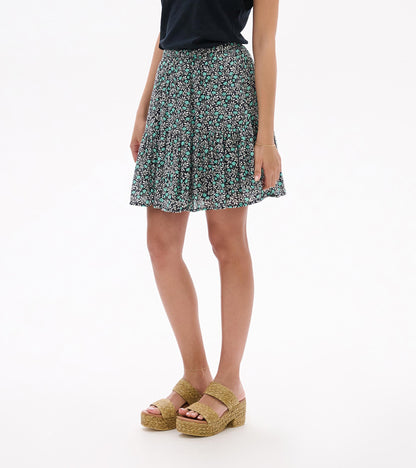 Mini flounce skirt with black, white and teal floral vine print, shown on model from front