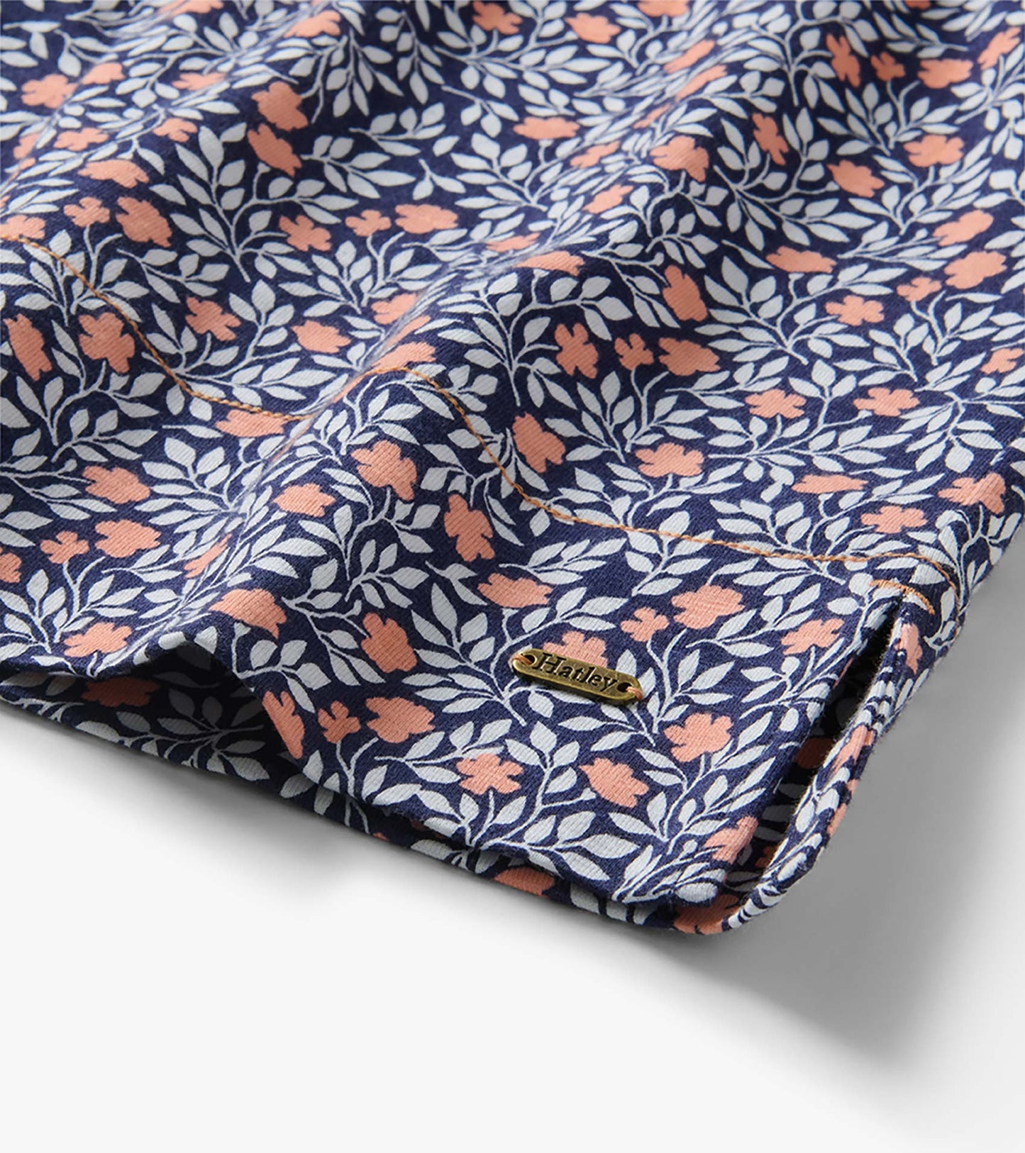 Folded navy dress with peach and white floral vine print and small side logo tag