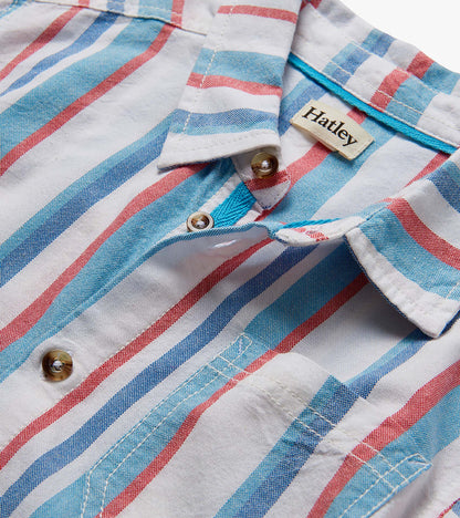 Close-up of a white woven button-down shirt with blue and red nautical stripes and brown buttons.