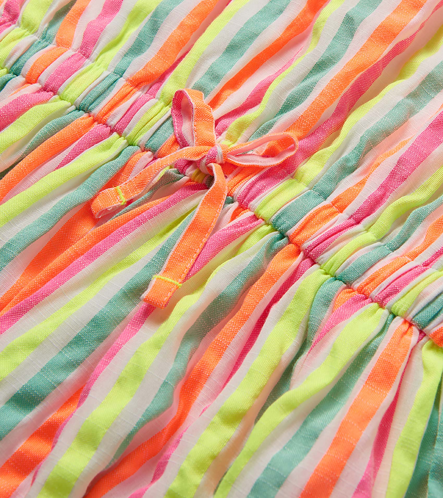 Close-up of a neon striped woven dress with gathered elastic waist and tie detail