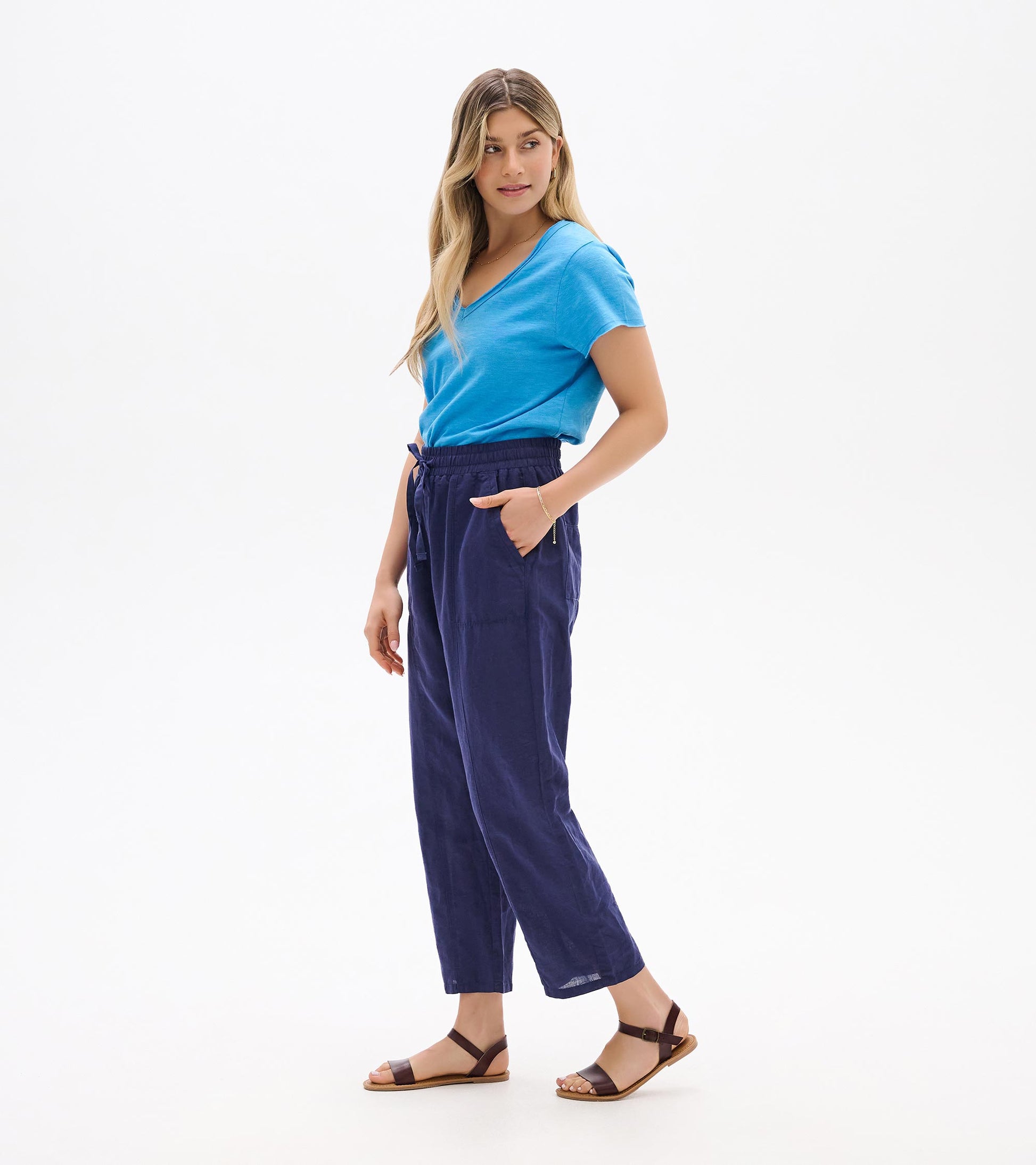 Woman wearing navy straight-leg pants with an elastic waist and side pockets, shown in side view.