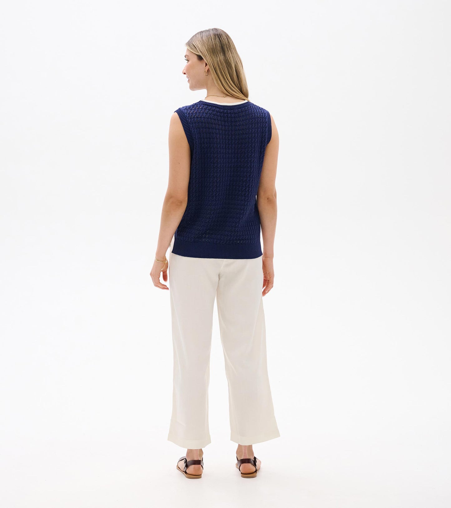 Back view of a navy blue knit sleeveless tank top with ribbed trim and textured pattern