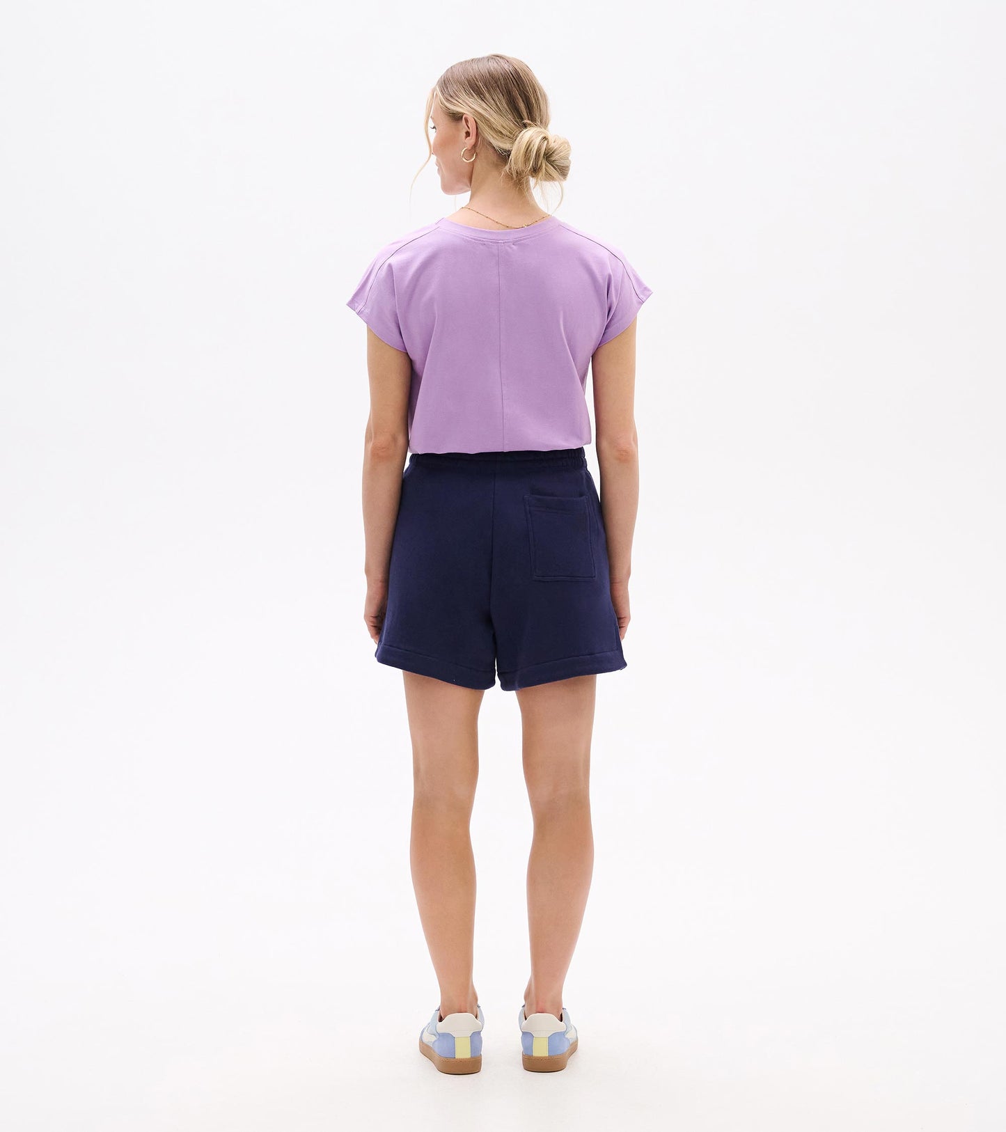 Back view of navy pull-on shorts with elastic waist and back patch pocket, worn with a lavender top.