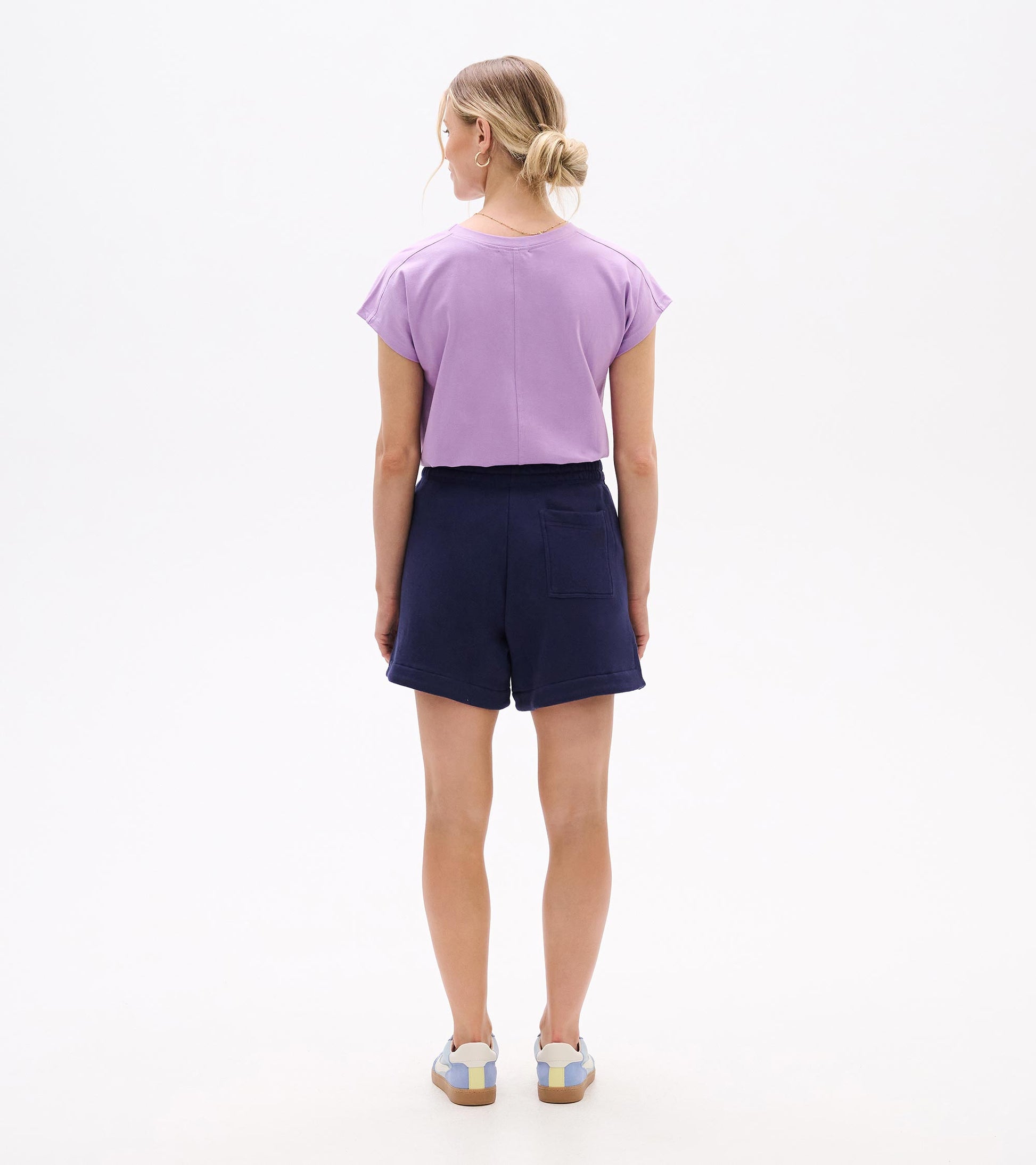 Back view of navy pull-on shorts with elastic waist and back patch pocket, worn with a lavender top.