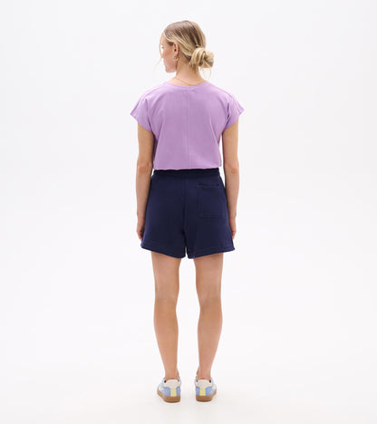 Back view of navy pull-on shorts with elastic waist and back patch pocket, worn with a lavender top.