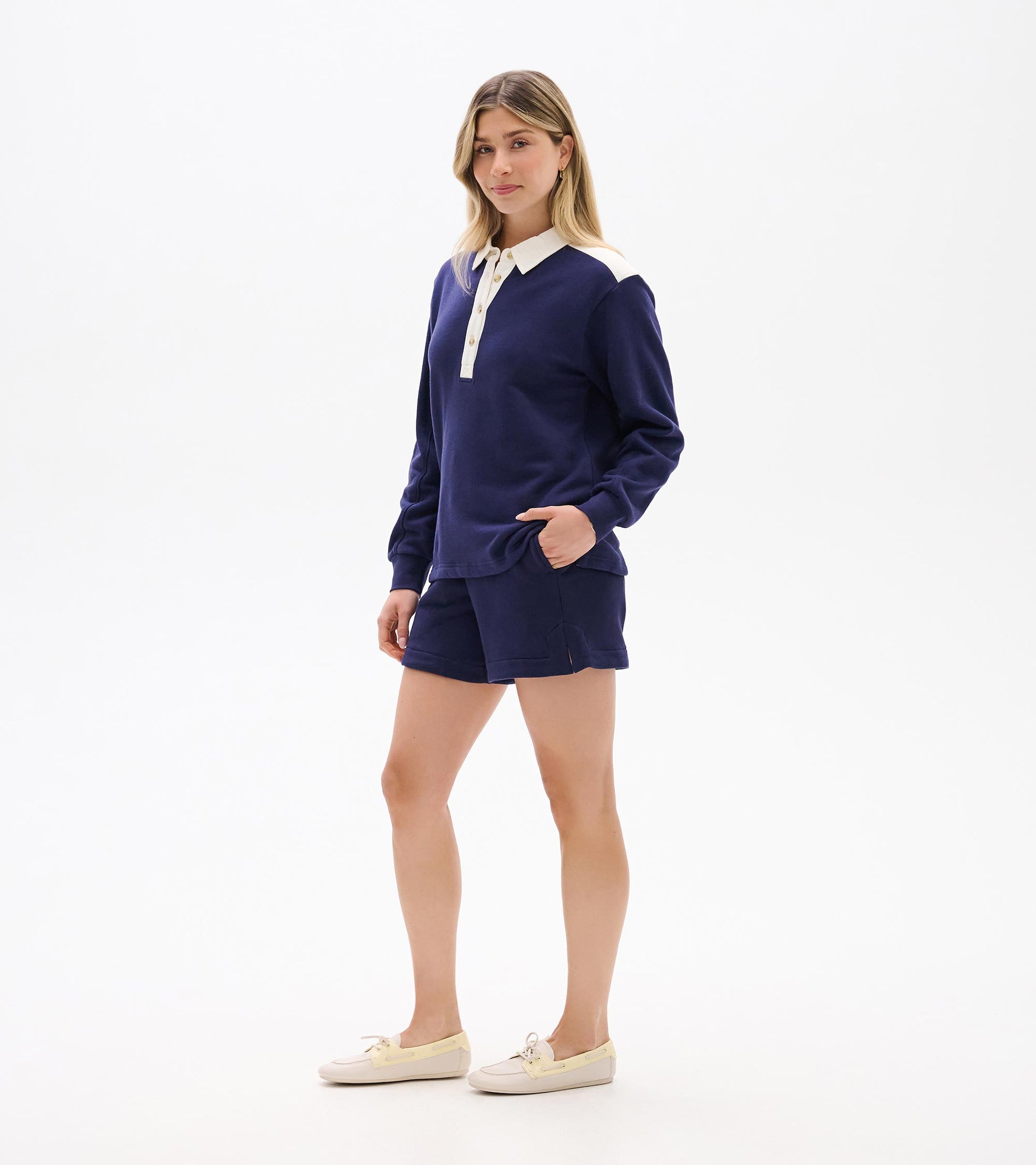 Woman wearing navy long-sleeve polo top with white collar and button placket, front view