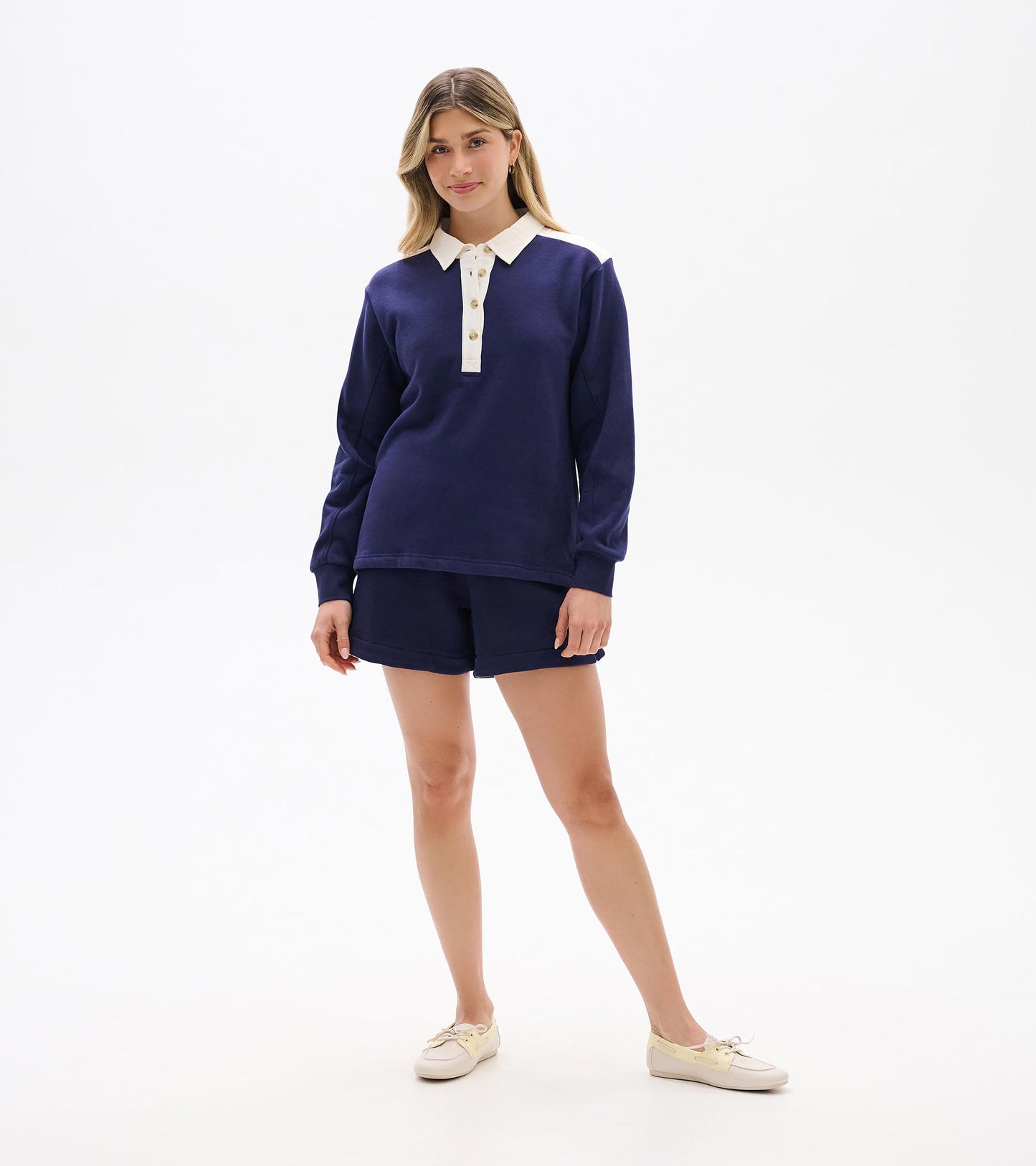Navy long-sleeve polo top with white collar, placket, and shoulder accents, shown on a model front view.