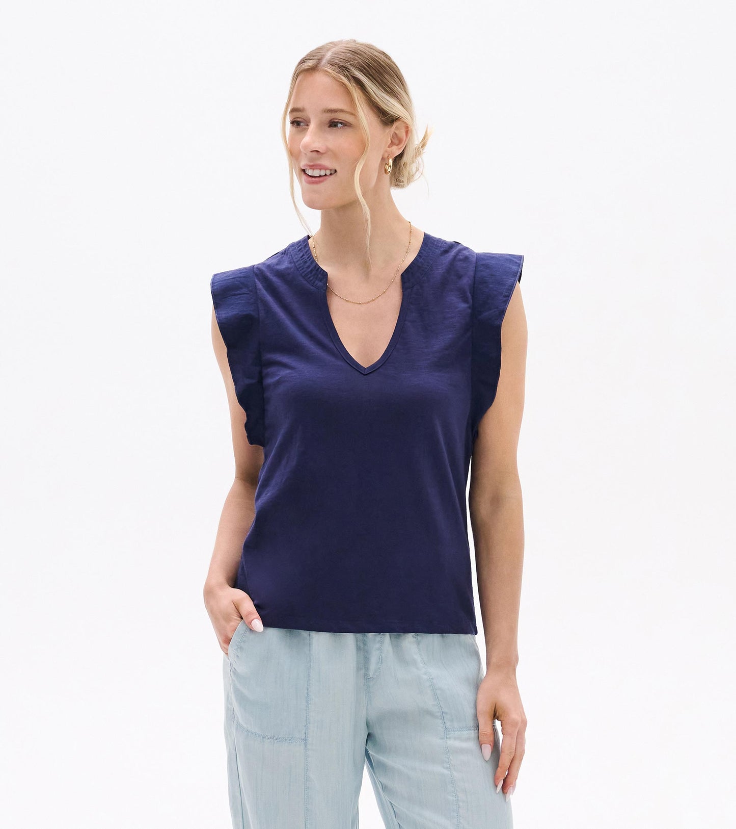 Navy sleeveless V-neck tank top with ruffled shoulders and a relaxed fit, worn with light blue pants.