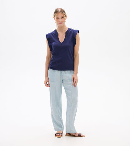 Woman wearing a navy sleeveless V-neck tank top with ruffled shoulders, front view